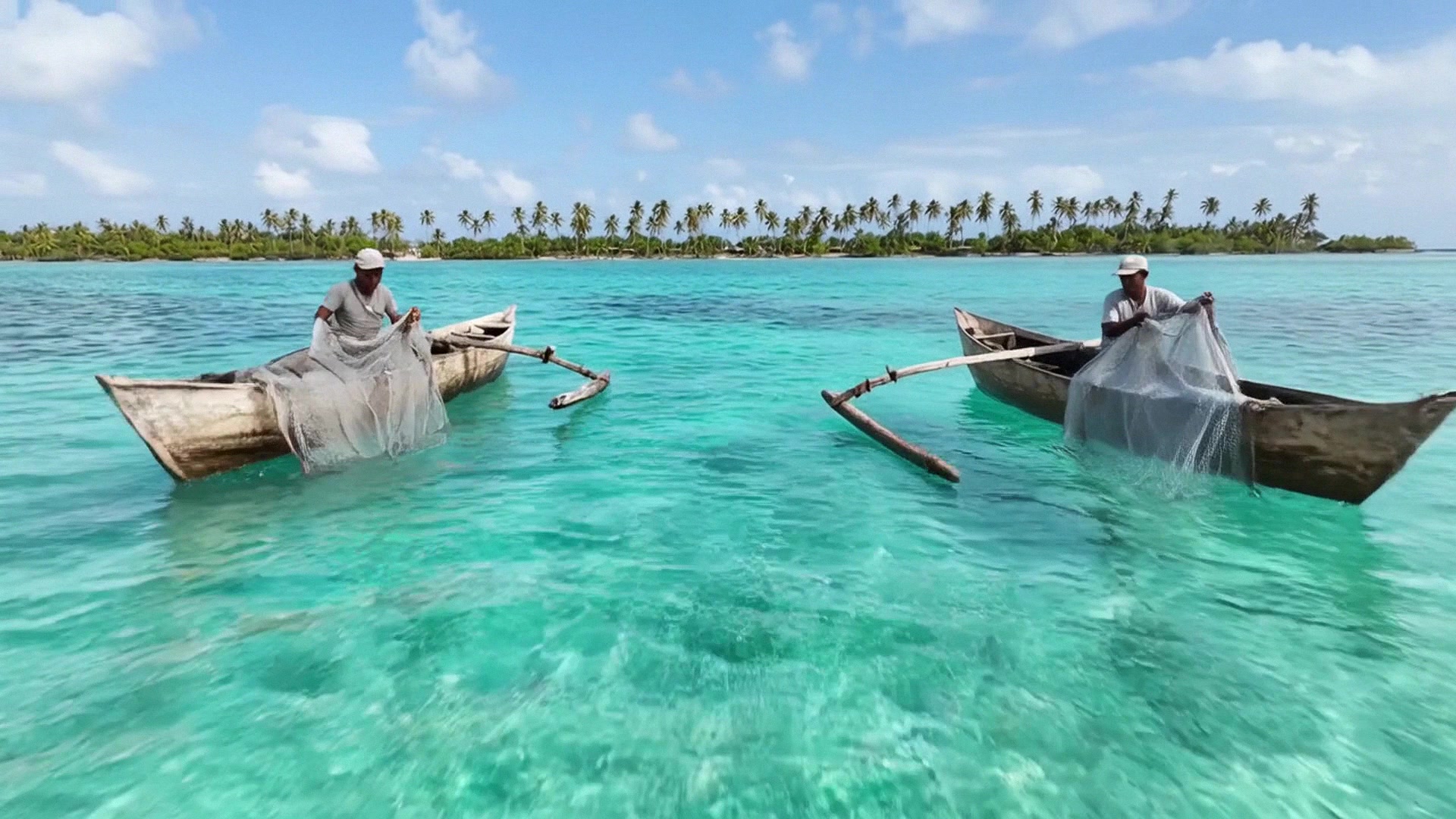 Kids splash in shallow lagoon water as the camera skims past.
